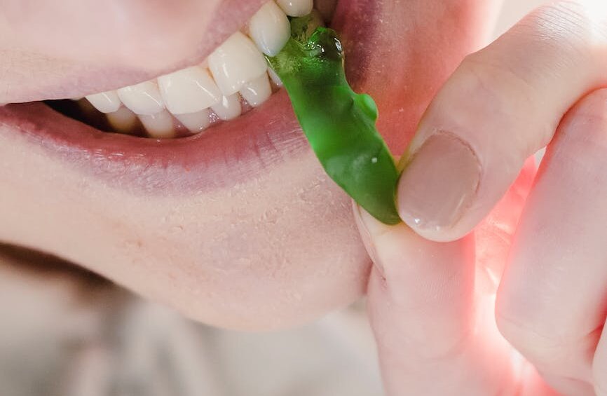 cheerful woman biting sweet green marmalade