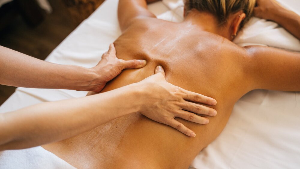 a person massaging a client s bare back