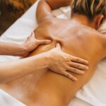 a person massaging a client s bare back