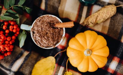 cinnamon stick on a chocolate drink beside pumpkin