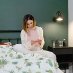 woman in white long sleeve shirt sitting on bed